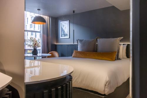 a bedroom with a bed and a table and a window at Velvet Hotel in Manchester