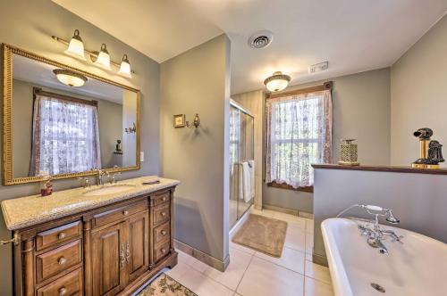 La salle de bains est pourvue d'une baignoire, d'un lavabo et d'un miroir. dans l'établissement The Farm House with Deck and Historic Charm!, 