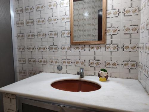 ein Bad mit einem Waschbecken und einem Spiegel in der Unterkunft Casa pé na areia - 4m da praia! in São Pedro da Aldeia