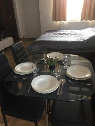 a table with plates and glasses on it with a bed at Apartmány Silvia in Dunajská Streda