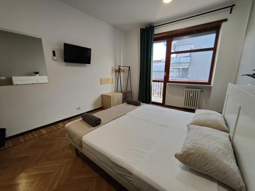Un dormitorio con una gran cama blanca y una ventana. en Affittacamere - Santa Rita Rooms, en Turín
