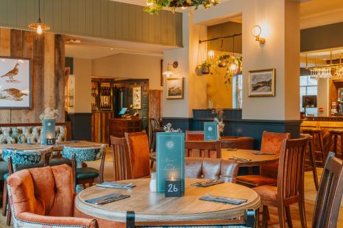 a dining room with tables and chairs in a restaurant at Grouse & Claret, Matlock by Marston's Inns in Matlock