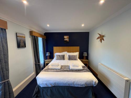 a bedroom with a large bed with two pillows at The Ship Inn - Winner Best Hotel Experience 2024 Visit Scotland in Gatehouse of Fleet