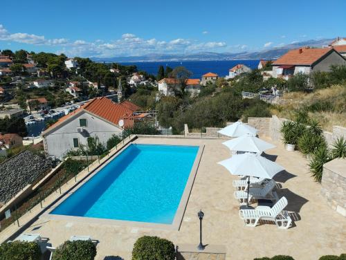 a swimming pool with chairs and umbrellas on a house at Villa Sanja, Splitska in Splitska