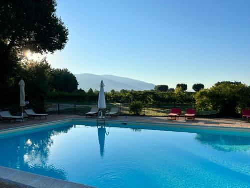 a large swimming pool with chairs and umbrellas in front at Agriturismo Podere La Fornace in Assisi