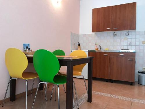 Poljica的住宿－Apartments Semafor，厨房配有桌子和一些绿色椅子