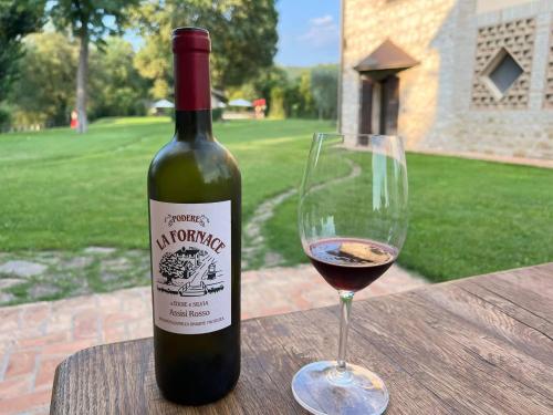 una bottiglia di vino e un bicchiere su un tavolo di Agriturismo Podere La Fornace ad Assisi