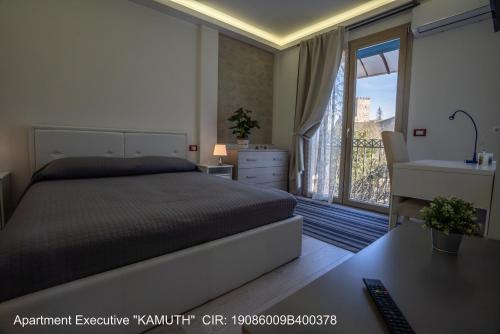 1 dormitorio con cama, escritorio y ventana en ROCCA DI CERERE Self Check-in Apartments, en Enna