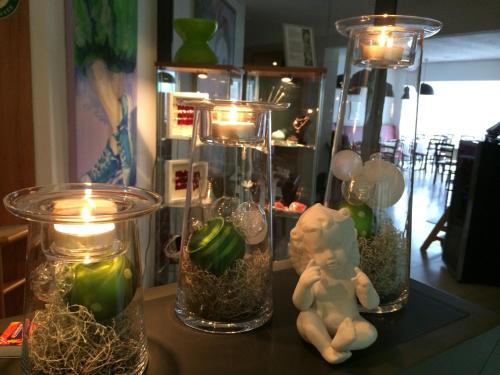 a table with three glass jars with candles and a doll at Hotel am Müritz-Nationalpark in Waren