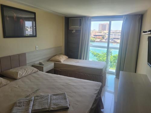 a hotel room with two beds and a large window at Ibiza Barra Hotel in Rio de Janeiro