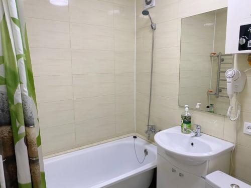 ein Badezimmer mit einem Waschbecken, einer Badewanne und einem Spiegel in der Unterkunft Apartment on Maylin 30 12 in Turksib