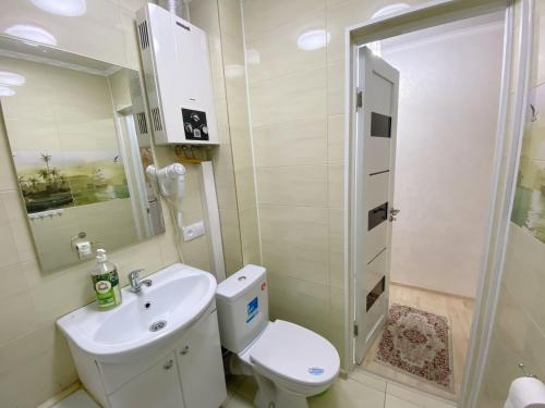 ein Bad mit einem WC, einem Waschbecken und einer Dusche in der Unterkunft Apartment on Maylin 30 12 in Turksib