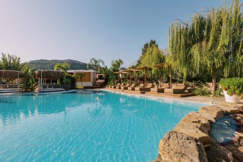Kouros Exclusive Hotel & Suites - Adults Only في فاليراكي: مسبح كبير مع ماء أزرق في منتجع
