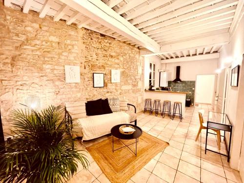 un salon avec un canapé et un mur en pierre dans l'établissement Le MOKA Charmant Appartement au coeur de ville, à Nîmes