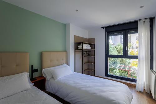 two beds in a room with a window at Apartamentos Congreso, Parking gratuito in Logroño