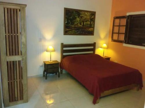 1 dormitorio con 1 cama roja y 2 lámparas en Chalés Azuleto - Ilhabela, en Ilhabela