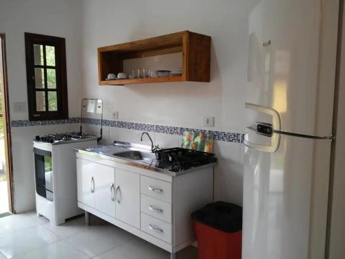 a kitchen with a sink and a refrigerator at Chalés Azuleto - Ilhabela in Ilhabela