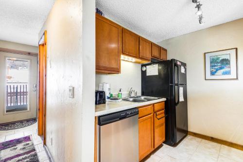 a kitchen with wooden cabinets and a black refrigerator at 2 Bed 1 Bath Apartment in Wildernest, CO in Silverthorne