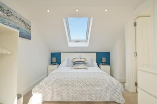 a bedroom with a white bed with a window at Stylish Herne Bay apartment by the sea in Kent