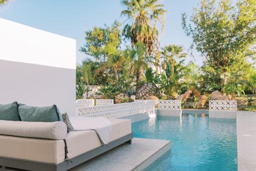 Kouros Exclusive Hotel & Suites - Adults Only في فاليراكي: غرفة معيشة مع أريكة بجانب مسبح