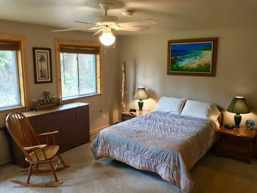 a bedroom with a bed and a chair and two windows at Boulder Creek Cabin by Casago McCall - Donerightmanagement in Donnelly
