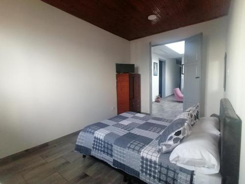 um quarto com uma cama com um cobertor azul e branco em ANGIE`s HOUSE em Manizales