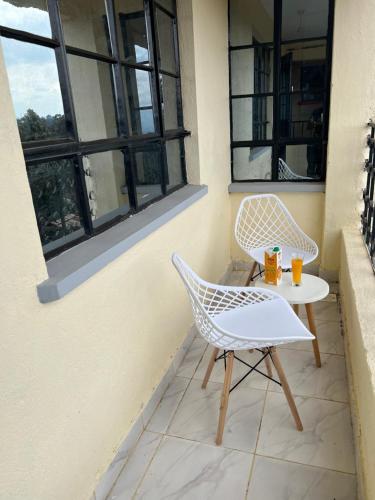 a patio with two chairs and a table and two windows at Ruby Modern Homes-2br-Nyeri, King'ong'o-Knights in Nyeri