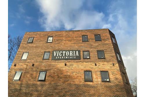 un edificio de ladrillo alto con un cartel. en OYO Victoria Apartments en Middlesbrough