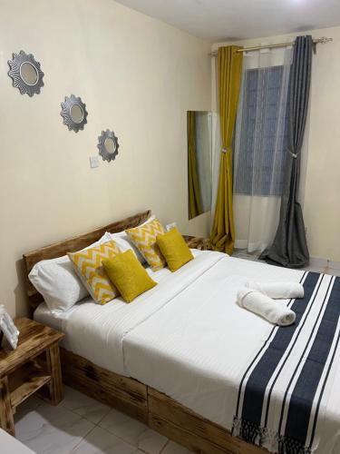 1 dormitorio con 1 cama grande con almohadas amarillas y azules en Ruby Modern Homes-2br-Nyeri, King'ong'o-Knights en Nyeri