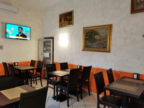 uma sala de jantar com mesas e cadeiras e uma televisão de ecrã plano em Hotel Orchidea em Turim
