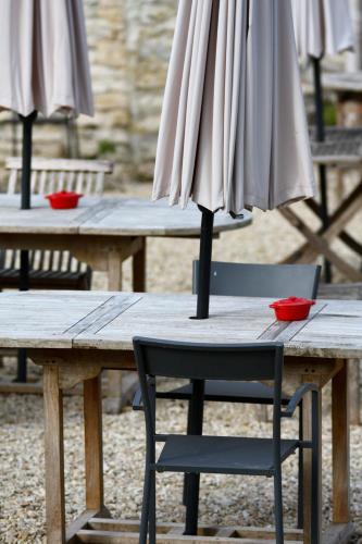 a wooden table with a chair and an umbrella at Logis La Source Bleue in Gudmont