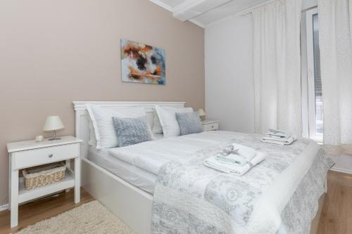 een witte slaapkamer met een wit bed en een raam bij Happy Apartments Mostar in Mostar