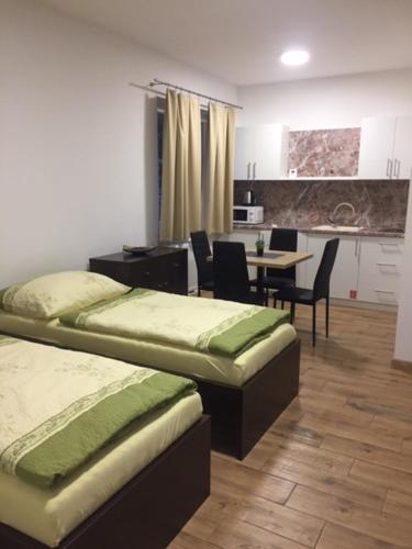 a room with two beds and a table and chairs at Apartmány Silvia in Dunajská Streda