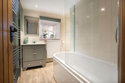 ein Badezimmer mit einer Badewanne und einem Waschbecken in der Unterkunft Pinewood Cottage - Newby Bridge in Lake Side