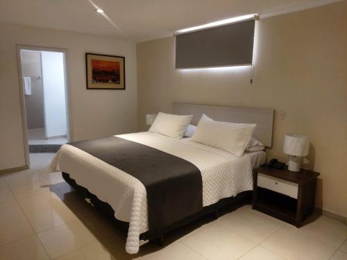 1 dormitorio con 1 cama grande con almohadas blancas en Hotel Ejecutivo Portoviejo, en Portoviejo