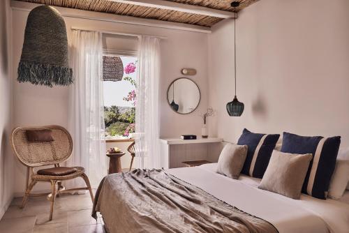 um quarto com uma cama, uma cadeira e uma janela em Dionysos Seaside Resort Ios em Mylopotas