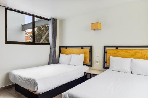 2 Betten in einem Zimmer mit 2 Fenstern in der Unterkunft Lago Zirahuén By HomiRent in Mexiko-Stadt