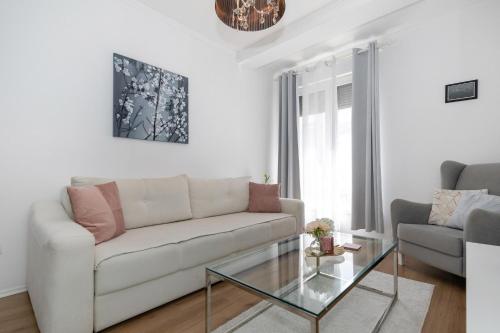 ein Wohnzimmer mit einem weißen Sofa und einem Glastisch in der Unterkunft Happy Apartment II in Mostar
