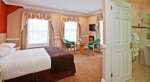 セント・マーティン・ガーンジーにあるLa Villette Hotelのベッド、テーブル、椅子が備わるホテルルームです。