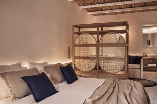 a bedroom with a large white bed with blue pillows at Dionysos Seaside Resort Ios in Mylopotas