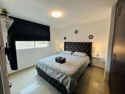 1 dormitorio con 1 cama con cabecero negro y ventana en Luxury Suite, en Guayaquil
