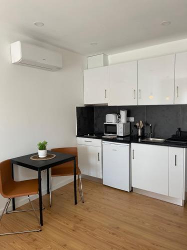 a kitchen with white cabinets and a black table at Paraíso do Sítio 2 in Nazaré