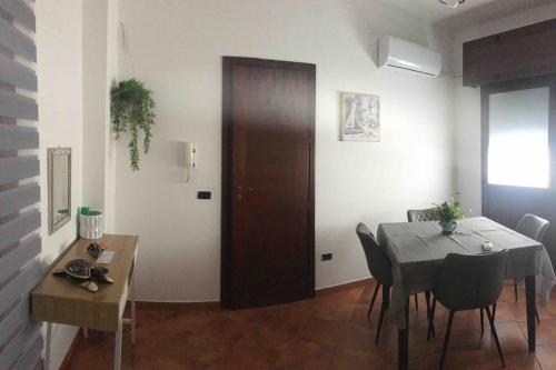 a dining room with a table and a wooden door at Alloggio incantevole/ bedsitting-room in Altavilla Milicia