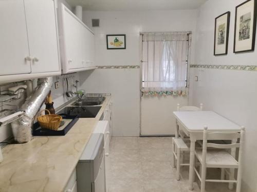 kuchnia z białymi szafkami, zlewem i stołem w obiekcie Mirador de San Matias w mieście Covaleda