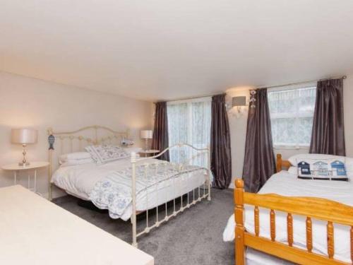 1 dormitorio con 2 camas y 2 ventanas en Harbour View en Kingswear
