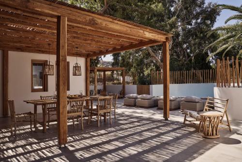 a patio with a wooden pergola and a table and chairs at Dionysos Seaside Resort Ios in Mylopotas