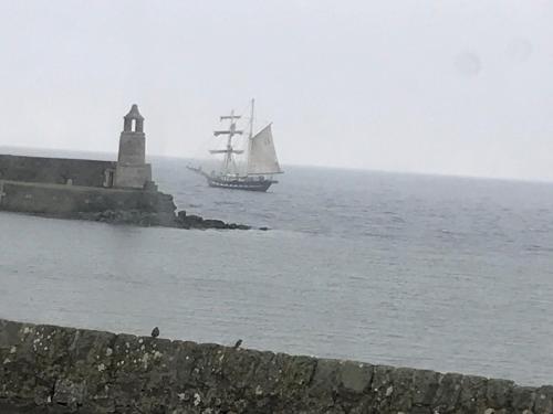a sail boat in the water next to a lighthouse at Curlew Cottage and Sunset View in Port Logan