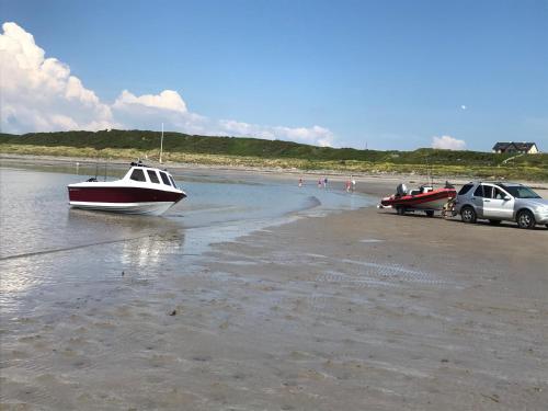 a boat and a car on the beach at Curlew Cottage and Sunset View in Port Logan