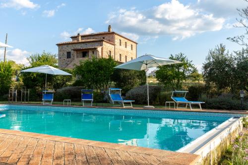 een zwembad met blauwe stoelen en parasols bij Villa ALTA in Villastrada