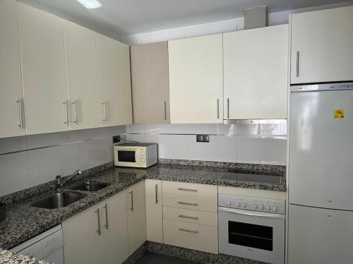 a kitchen with white cabinets and a sink and a microwave at Rondabella 3 Parking Gratis Centro in Ronda
